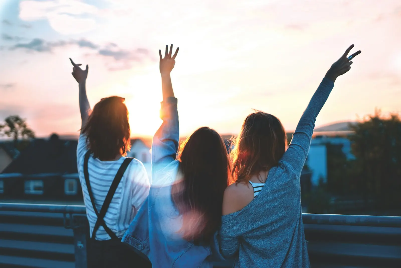 Three friends with their arms in the air at sunset